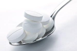 A spoon filled with white pill tablets.